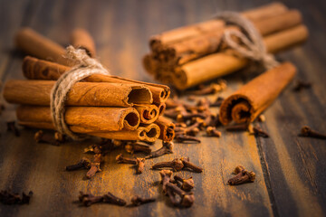 Christmas spices and baking ingredients: cinnamon sticks and cloves on wooden kitchen table