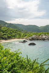 Sunny view of Carbo San Juan Beach in Tayrona national park, South America, Columbia. Some rocks in the warm ocean at a lagoon near Santa Marta. Vibrant and green jungle