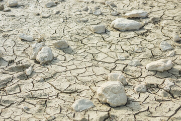 white stones on the ground from a dried up pond with cracks