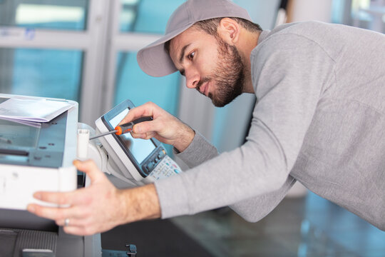 young male technician is repairing a printer at office