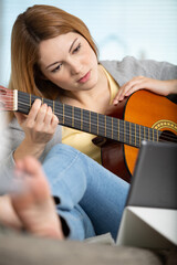 happy smiling woman using guitar and tablet