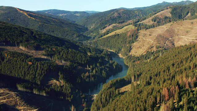 Flyover looking down on Olt River tributary in valley, Hasmas Mountains Romania