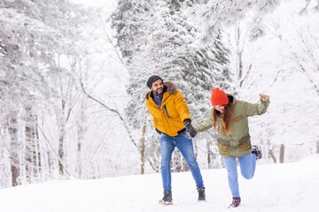 Fototapeta na wymiar Couple having fun running in the snow while on winter vacation