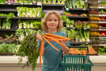 Child with carrot. Child buying fruit in supermarket. Little boy buy fresh vegetables in grocery store. Kid choosing vegetables. Healthy food.