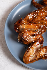 Close-up on a blue plate are wings cooked in teriyaki sauce. A dish of Asian cuisine.