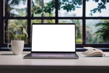 Modern laptop with blank white screen for copy replacement, cozy home interior with wide forest window view