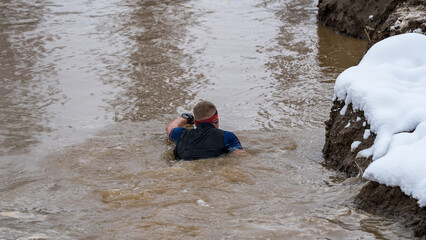 Ein Sportler in einem Wassergraben während eines Hindernislaufs