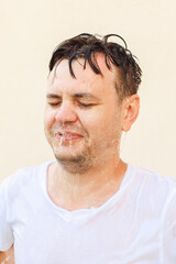 Obraz premium Young 32 years old european white male with closed eyes in water splash on yellow background. Man portrait, stress shock concept, mental health, rain, emotions, face expression, water drops.