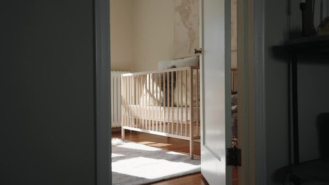 shot of a baby crib from outside of the nursery inside of a home