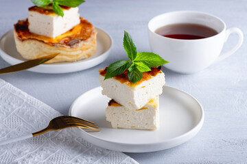 Cottage cheese casserole and cup of coffee on wooden light table. Cottage cheese casserole