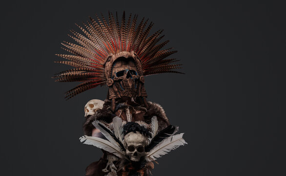 Shot of scary aztec necromancer holding staff with skull against grey background.