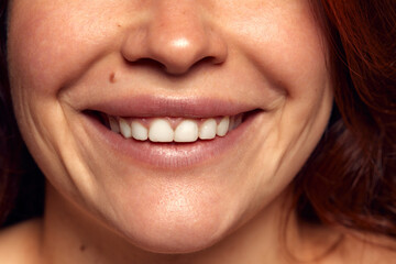 Close-up view of female perfect shape mouth with nude colored lipstick. Smiling. Cosmetological and dental care
