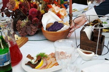 table setting for a festive dinner. waiter places a plate of bread on the table.