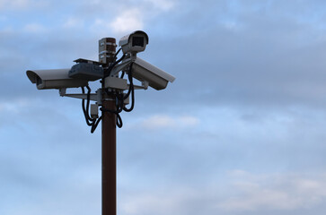 Outdoor security cameras on a pole against the sky