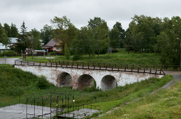 Fototapeta na wymiar Ancient arched brick bridge with cobbled pavement