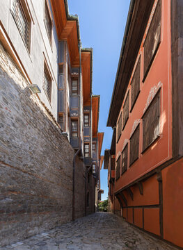 Narrow cobbled street unites 2 different architectural eras: ancient Roman Acropolis stonework and BULGARIAN REVIVAL MUSEUM EXHIBITION Renaissance building of 19th century, vertical, Plovdiv, Bulgaria