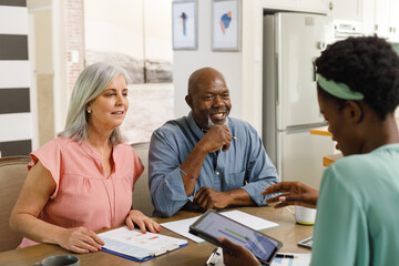Senior diverse couple talking with african american female financial advisor
