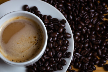 a cup of coffee with coffee beans, photographed from the top
