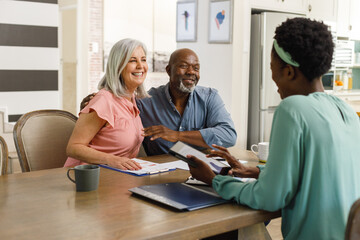 Happy senior diverse couple talking with african american female financial advisor