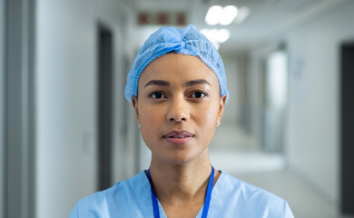 Portrait of biracial female healthcare worker in hospital corridor, copy space