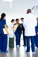 Vertical of diverse healthcare colleagues with tablet and files discussing in corridor, copy space