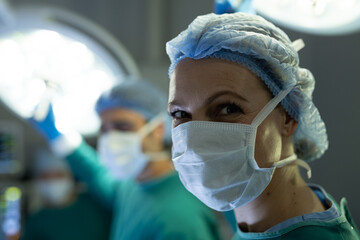 Portrait of smiling caucasian female surgeon during operation in theatre, with copy space