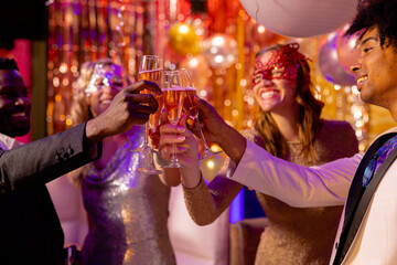 Four happy, diverse friends making a toast with glasses of champagne at a party in a nightclub