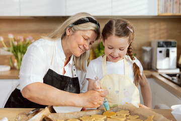 Happy delighted grandmother helping teaching young daughter baking cookies biscuits preparing...