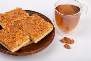 Almond cake with caramel, almond nuts, a cup of tea.