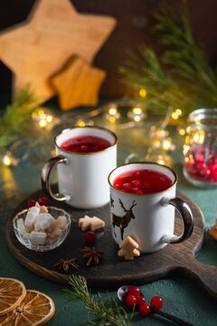 Spicy cranberry tea in two white mugs on a wooden board on a concrete green background in Christmas style. Merry Christmas concept.