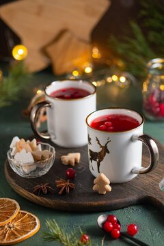 Spicy cranberry tea in two white mugs on a wooden board on a concrete green background in Christmas style. Merry Christmas concept.