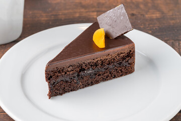 Orange and chocolate cake with cup of coffee on wooden table