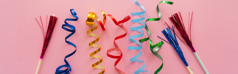Top view of colorful serpentine and drinking straws with tinsel on pink background, banner.