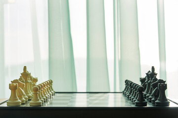Side view of Chess board ready for the game on the room close to window. Intellectual games and leisure activity concept