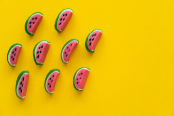 Top view of sweet candies in watermelon shape on yellow background.