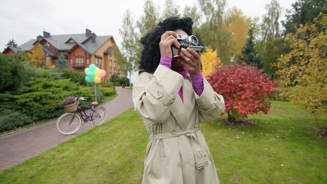 Portrait of a woman with dark, ethnic hair enjoy picturesque, weekend stroll. Cheerful female photographer snapping with a retro-styled camera outdoors. High quality 4k footage