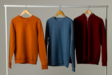 Coloured sweatshirts displayed on clothing rail and copy space on white background