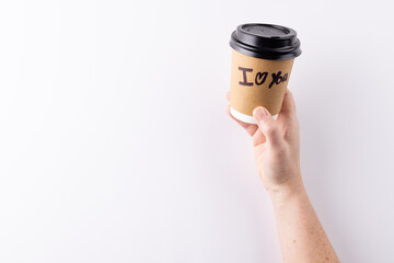 Hand holding takeaway coffee cup with i heart you text written on it, with copy space