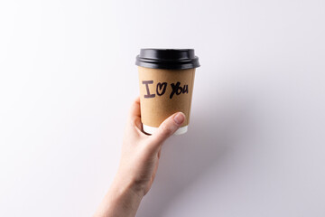 Hand holding takeaway coffee cup with i heart you text written on it, with copy space