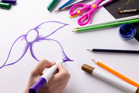 Hand drawing purple flower on paper and art materials on table top, with copy space