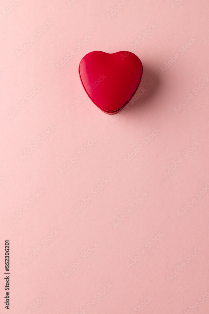 Poster overhead vertical image of red heart shaped box on pale pink background with copy space