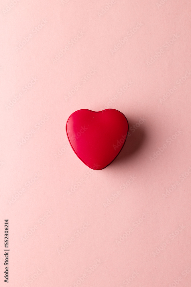 Poster overhead vertical image of red heart shaped box on pale pink background with copy space