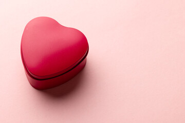 Close up of red heart shaped box on pale pink background with copy space