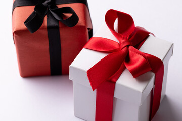 White and red gifts with red and black ribbons, on white background with copy space