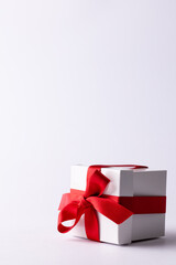 Vertical of white gift box tied with red ribbon, on white background with copy space