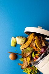 Vertical image of organic fruit and vegetable food waste spilling from open kitchen composting bin