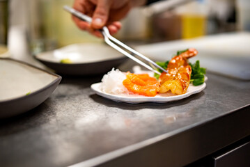 chef cooking slice salmon fish and shrimp with salad on kitchen