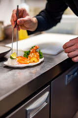 chef cooking slice salmon fish and shrimp with salad on kitchen