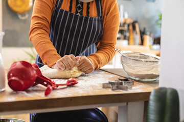 Midsection of biracial woman wearing hijab, standing in kitchen and baking
