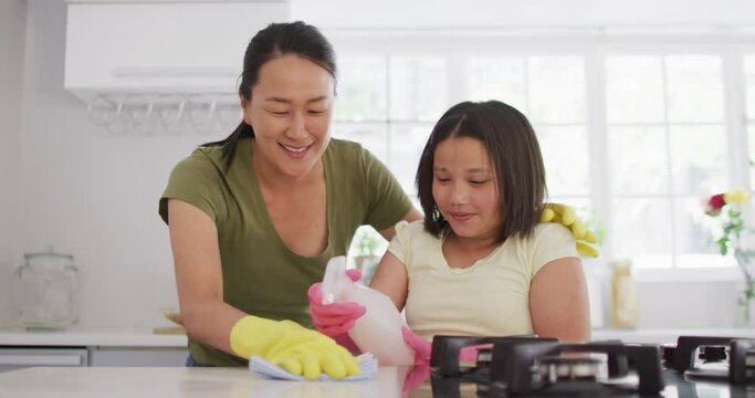 Video of happy asian mother and daughter cleaning kitchen